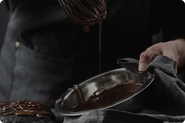 Chef whisking melted chocolate in a metal bowl