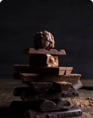 Stack of dark chocolate pieces on a dark surface